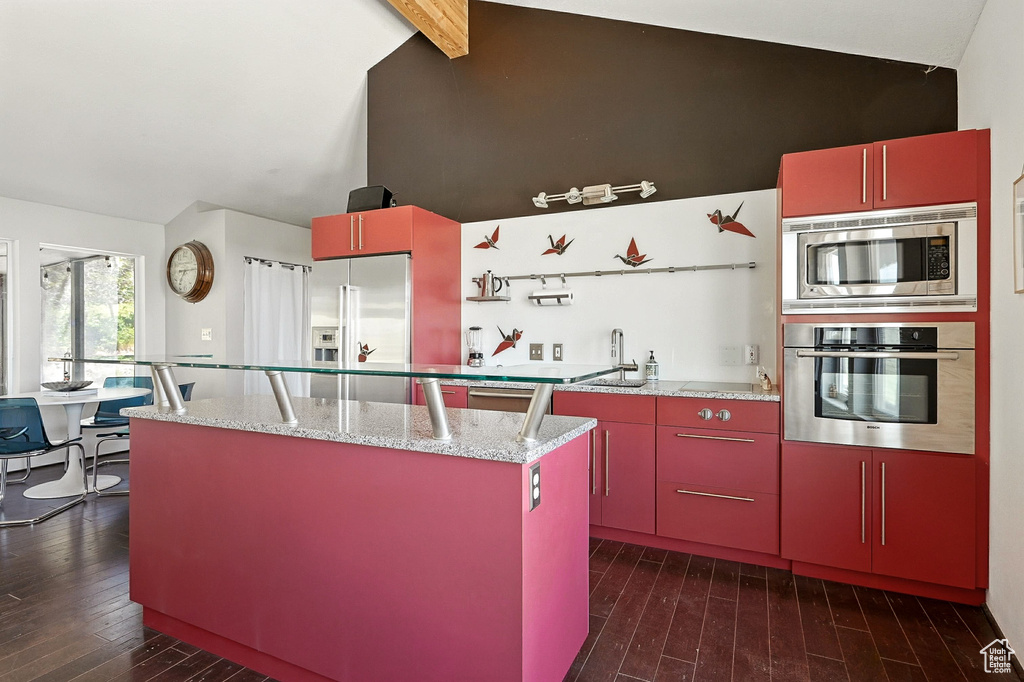 Kitchen featuring red cabinetry, appliances with stainless steel finishes, dark wood-type flooring, a center island, and open shelves