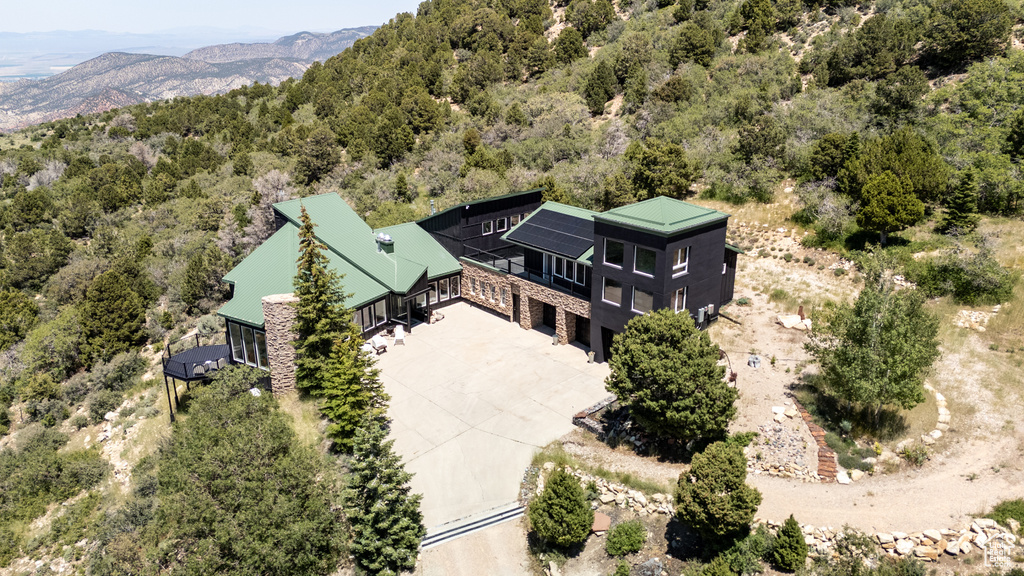 View of subject property with a mountain backdrop and a forest