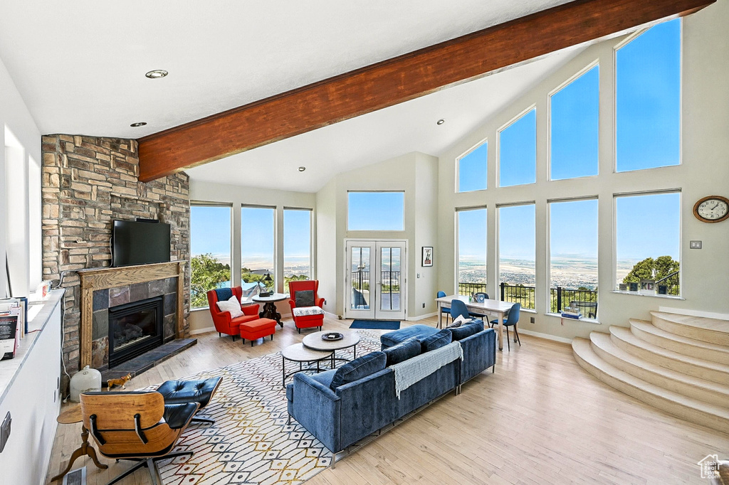 Living area with wood finished floors, plenty of natural light, and a stone fireplace