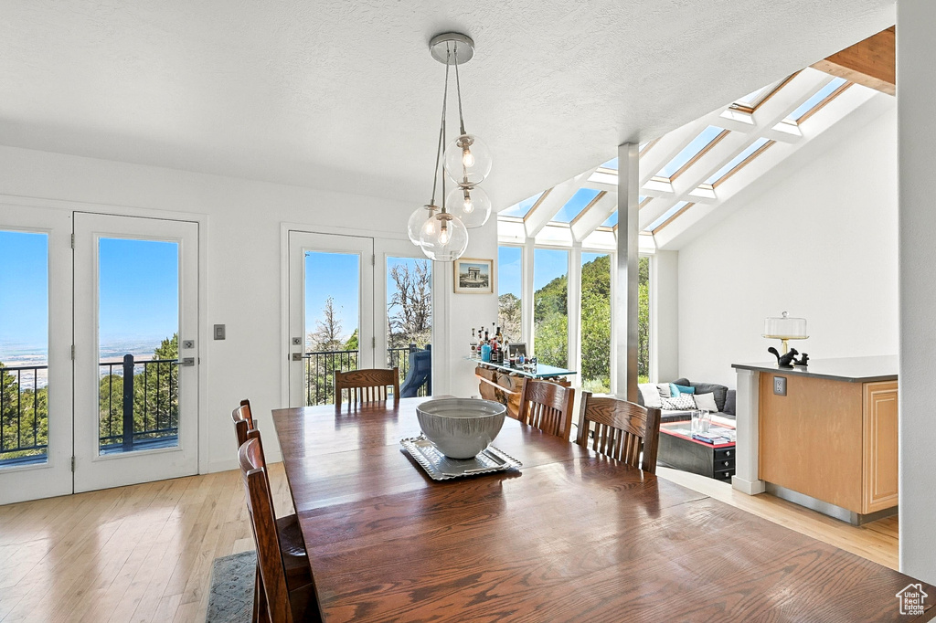 Dining area featuring light wood-style floors, lofted ceiling, and a skylight