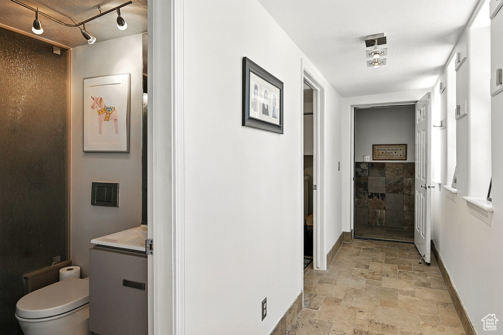 Hallway with light stone finish flooring and track lighting