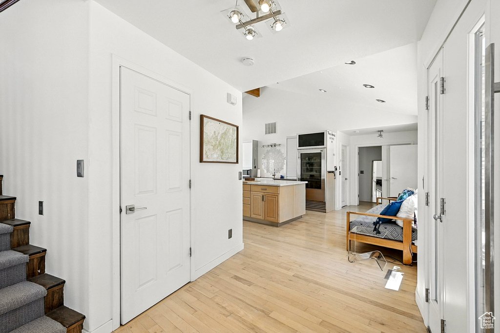Corridor featuring vaulted ceiling, light wood-type flooring, and stairs