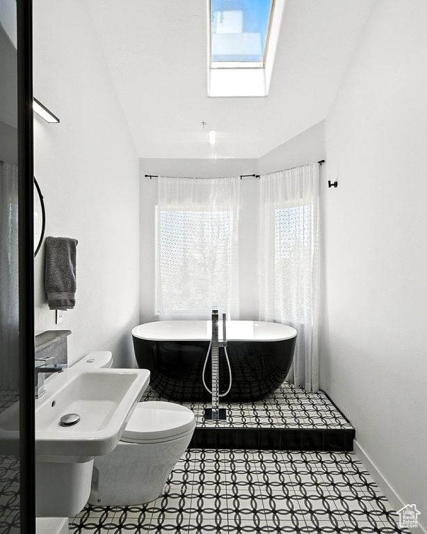 Full bath with a soaking tub, a skylight, and tile patterned floors