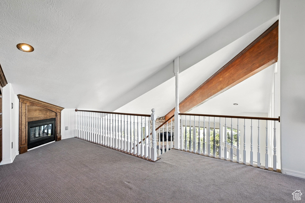Unfurnished living room featuring carpet, a glass covered fireplace, and vaulted ceiling