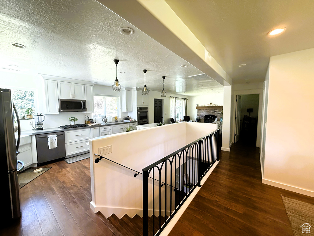 Kitchen featuring appliances with stainless steel finishes, a fireplace, plenty of natural light, white cabinets, and recessed lighting