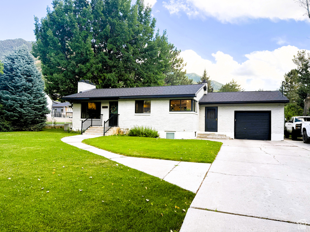 Tri-level home featuring brick siding, a garage, and a front lawn