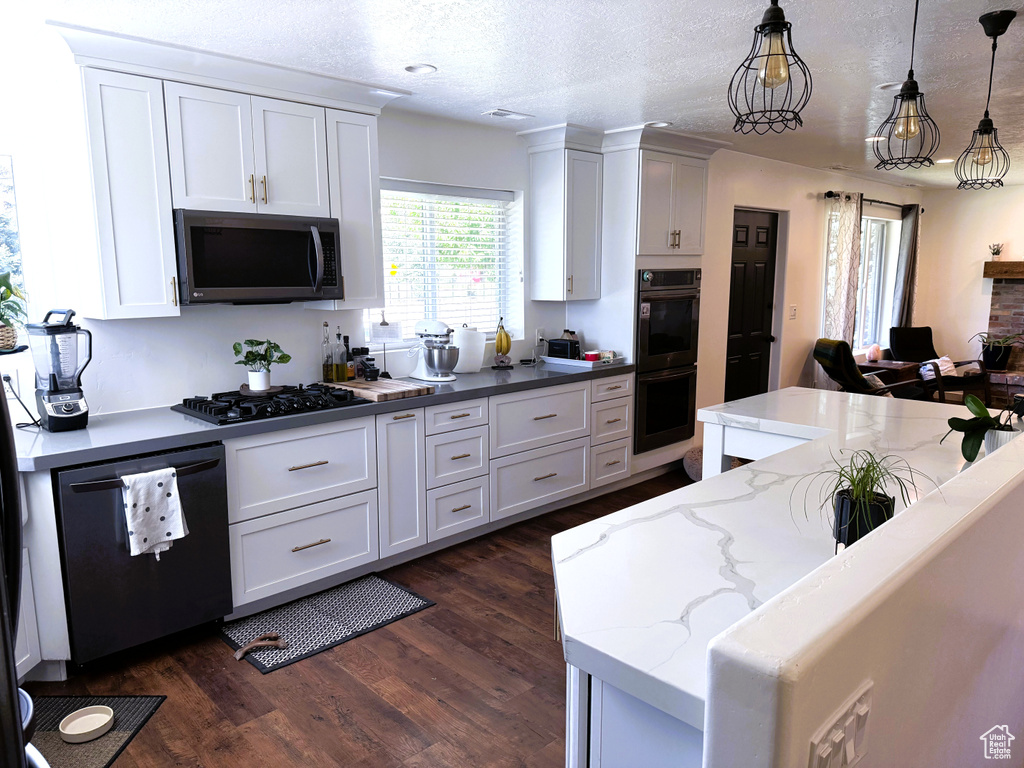 Kitchen featuring black appliances, dark wood-style floors, white cabinets, pendant lighting, and a textured ceiling