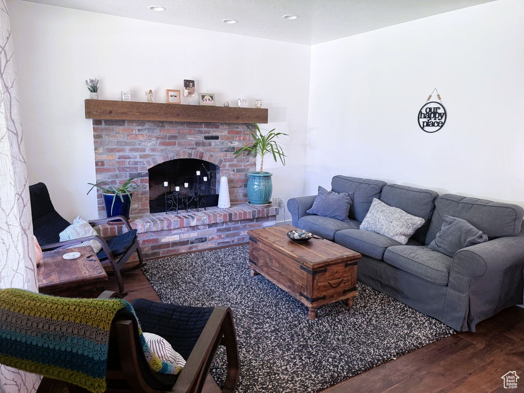 Living room featuring wood finished floors, a brick fireplace, and recessed lighting