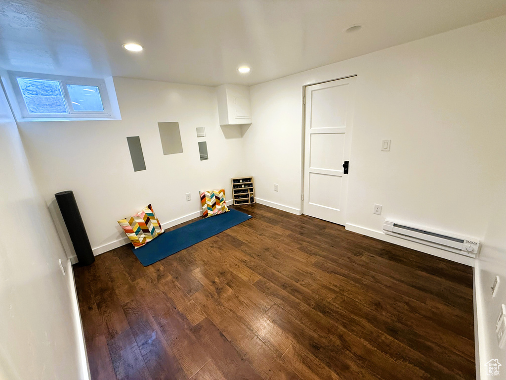 Below grade area with a baseboard radiator, dark wood-style floors, and recessed lighting