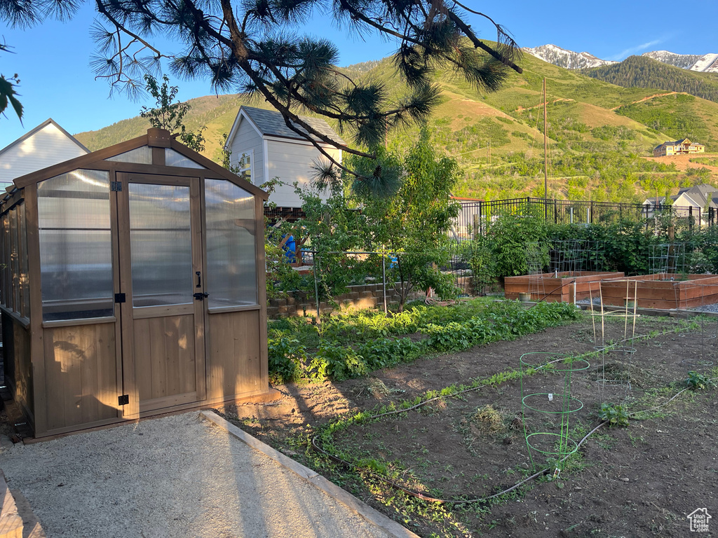 Exterior space with a vegetable garden, a greenhouse, an outbuilding, and a mountain view