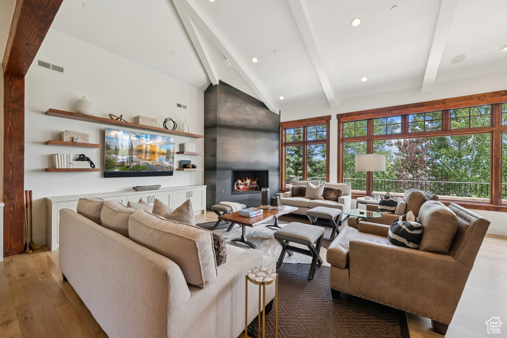 Living area featuring beam ceiling, wood finished floors, a large fireplace, high vaulted ceiling, and recessed lighting