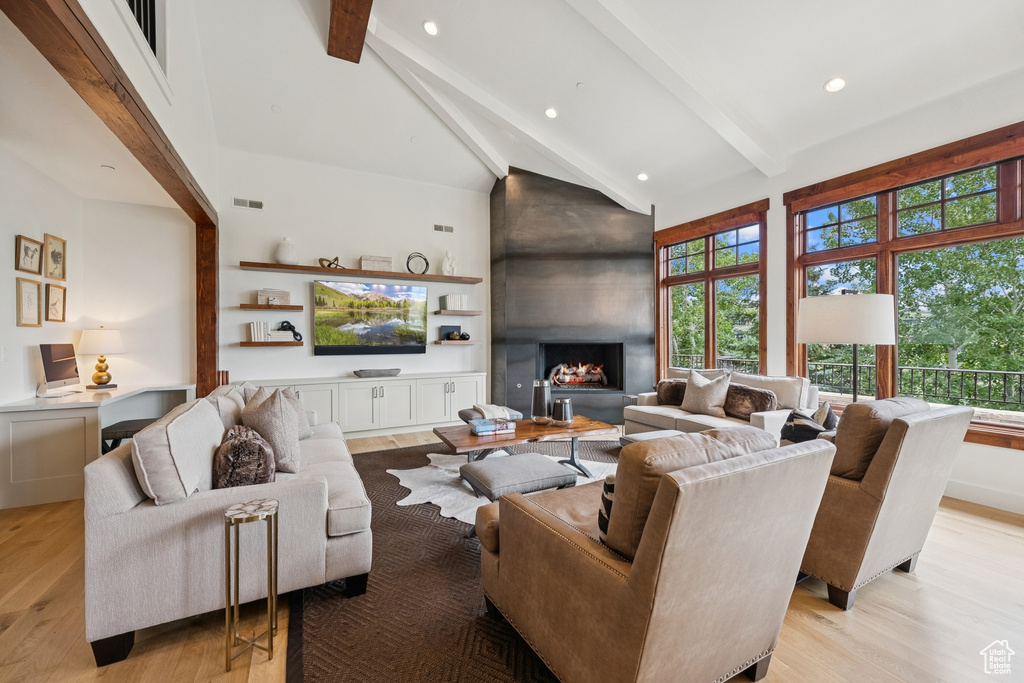 Living room featuring high vaulted ceiling, light wood-style floors, beamed ceiling, recessed lighting, and a large fireplace