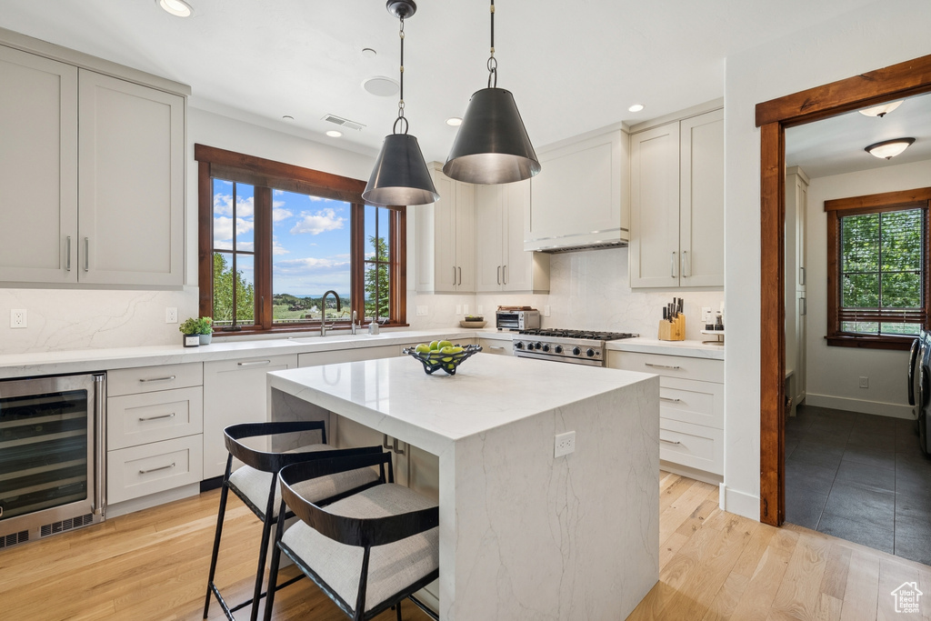 Kitchen featuring wine cooler, stove, a kitchen island, recessed lighting, and a kitchen bar