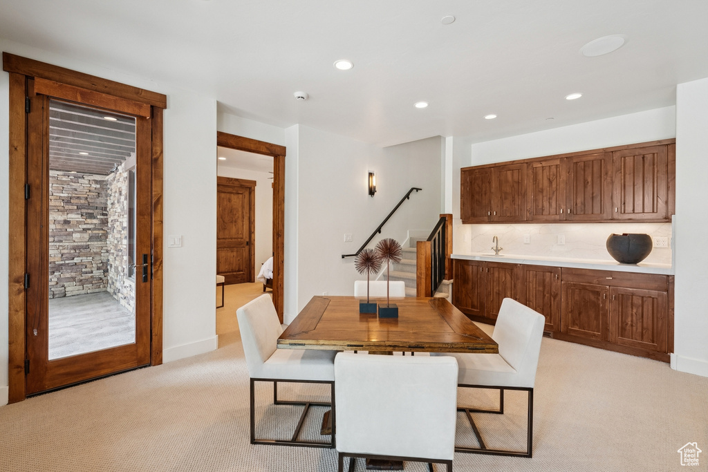 Dining area with light carpet and recessed lighting