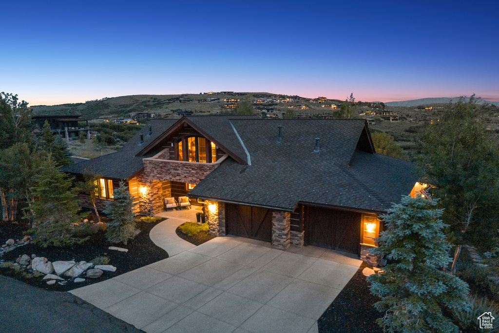 View of front of house with stone siding, concrete driveway, and a garage