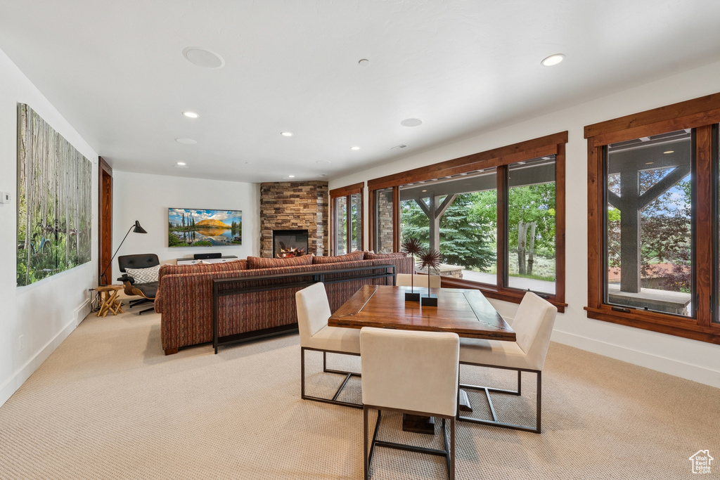 Dining area with recessed lighting, healthy amount of natural light, light colored carpet, and a stone fireplace