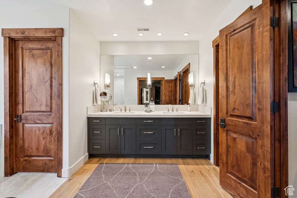 Full bath featuring double vanity, wood finished floors, and recessed lighting