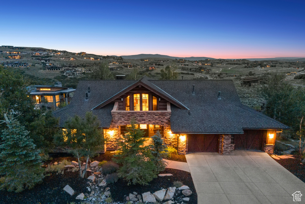 View of front facade featuring stone siding, driveway, and a mountain view
