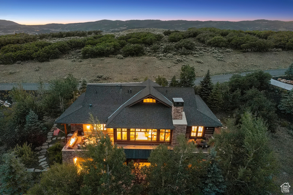 Back of property at dusk with stone siding and a mountain view