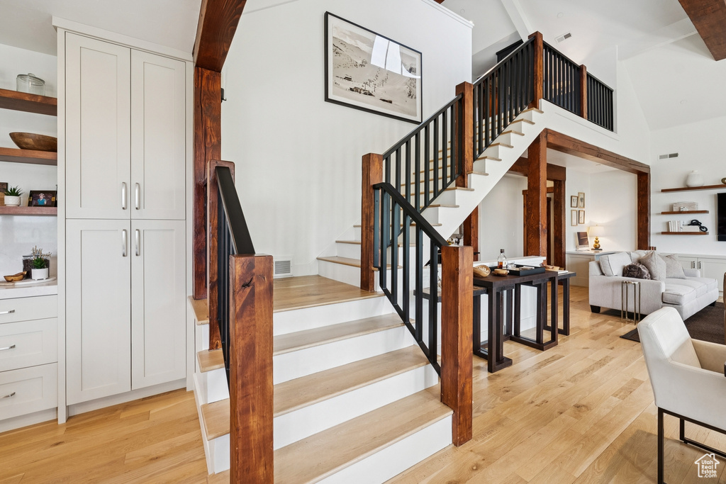 Stairway featuring wood finished floors and high vaulted ceiling