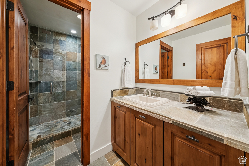 Bathroom featuring vanity, tiled shower, and recessed lighting