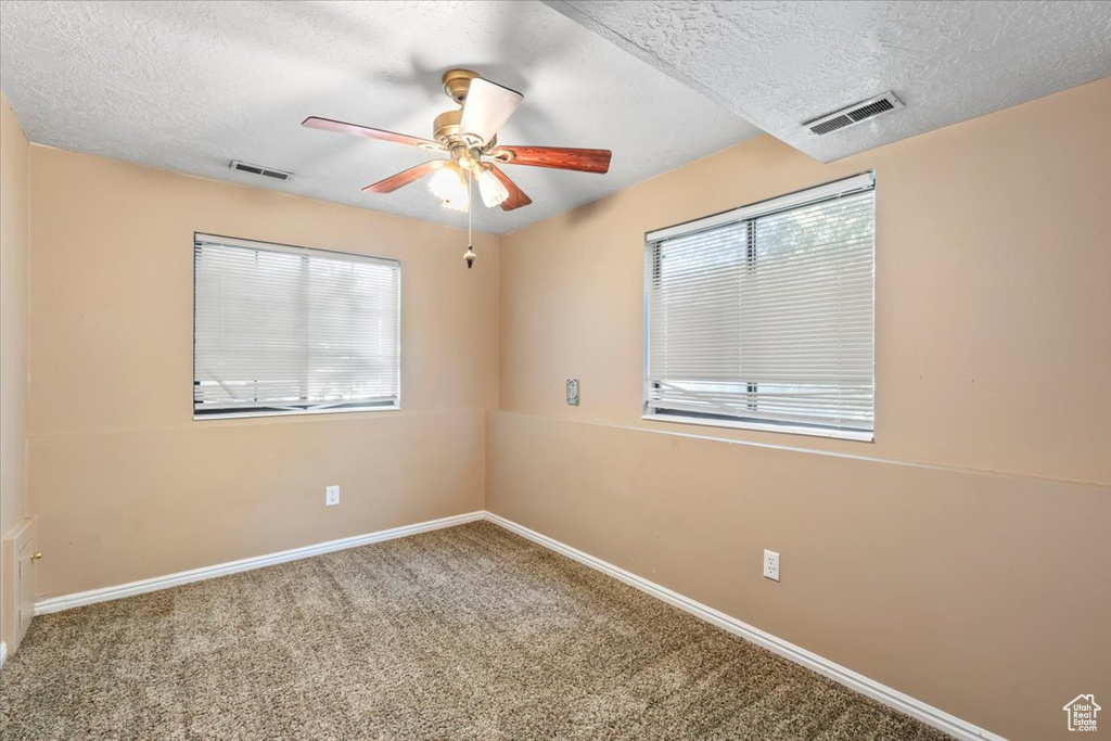 Carpeted spare room with ceiling fan and a textured ceiling