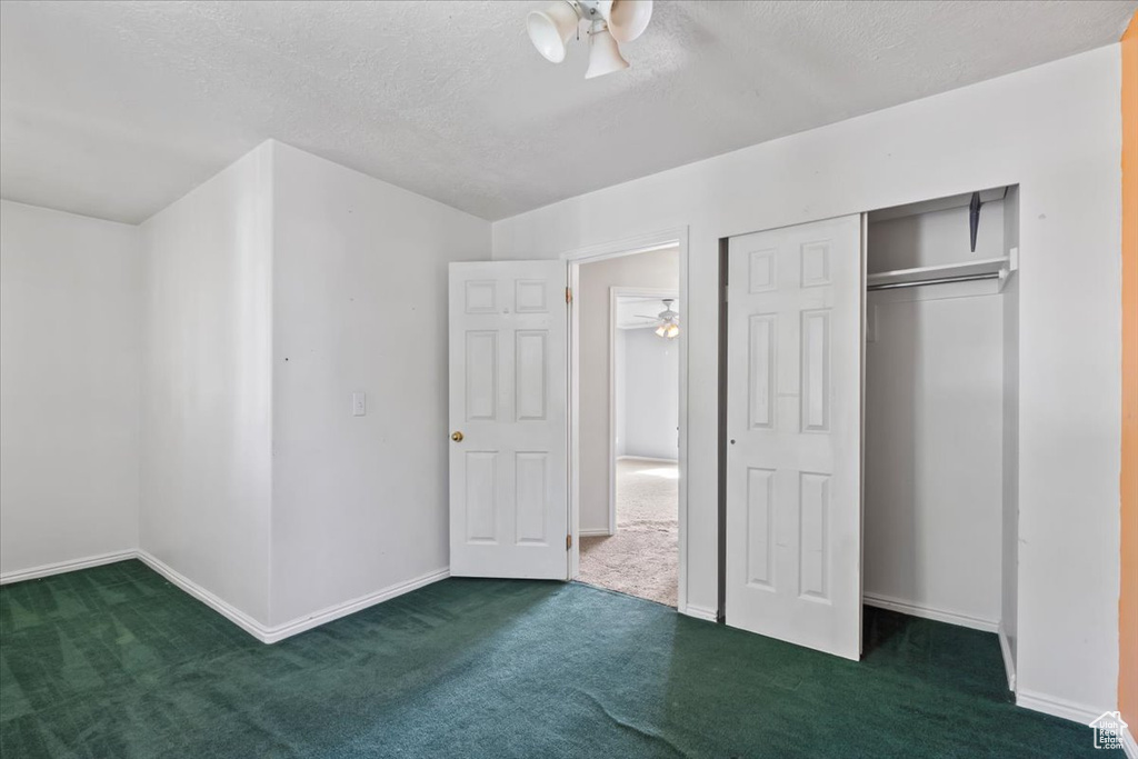 Unfurnished bedroom with carpet flooring, a textured ceiling, and a closet