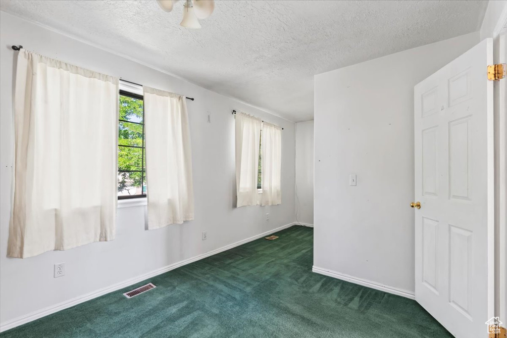 Carpeted spare room featuring a textured ceiling