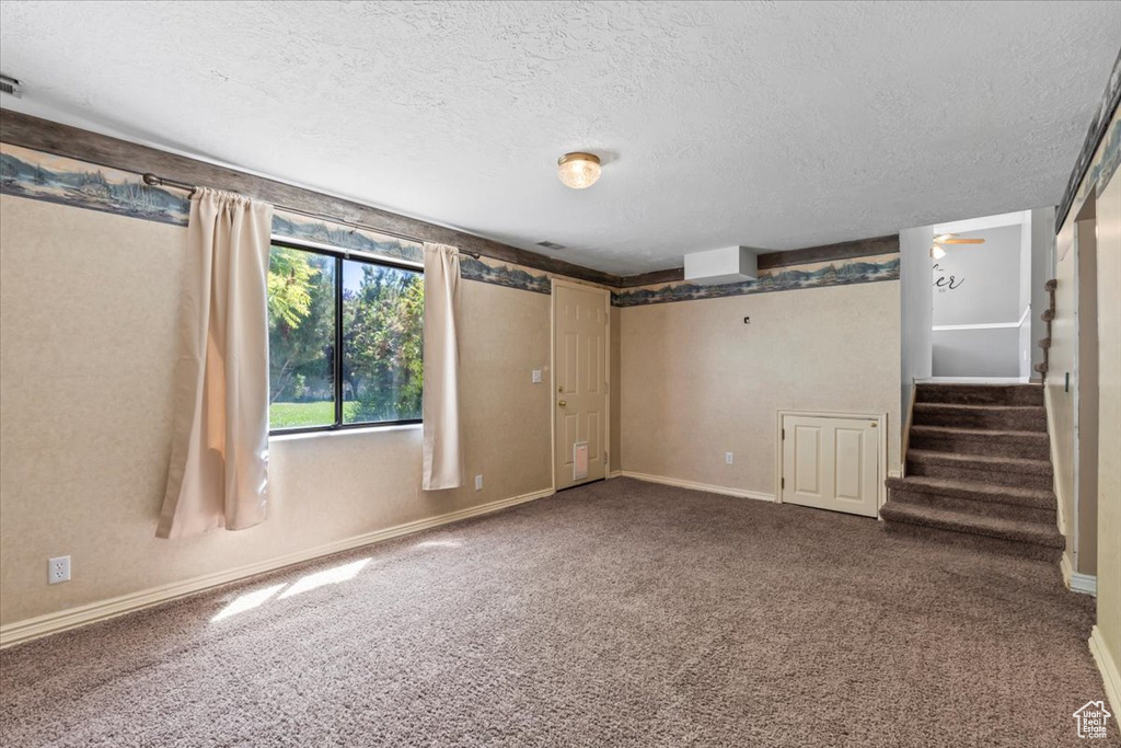 Basement featuring a textured ceiling, stairway, and carpet