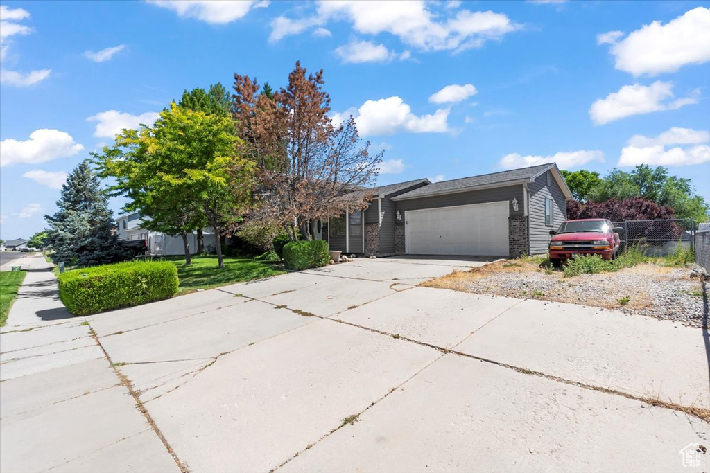 View of front of home with an attached garage, driveway, and brick siding