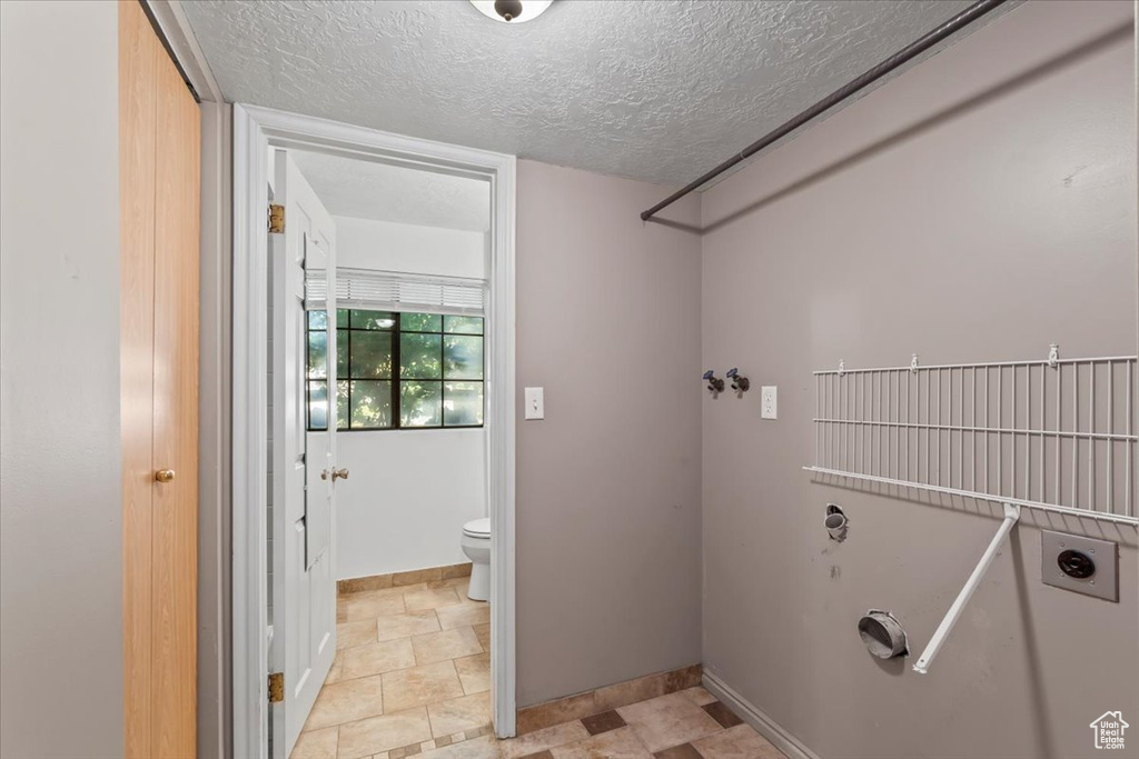 Laundry area featuring electric dryer hookup and a textured ceiling