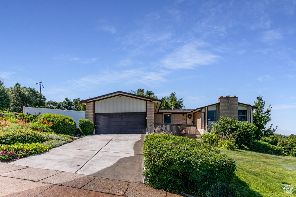 View of front of property with brick siding, a garage, and driveway