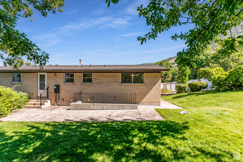 Back of house with a patio, a lawn, and brick siding