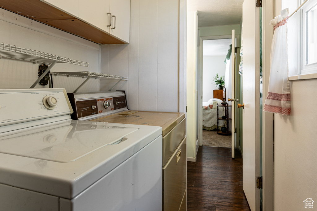 Washroom with cabinet space, dark wood finished floors, and separate washer and dryer