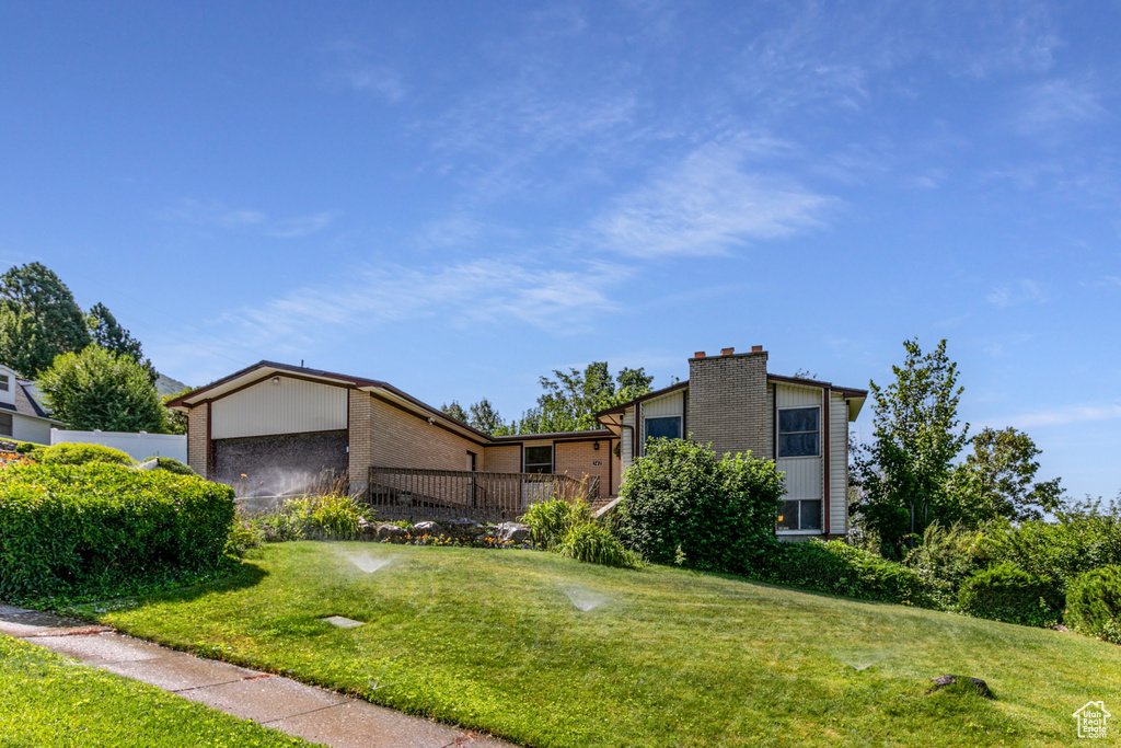Mid-century inspired home featuring brick siding, a front lawn, and a chimney