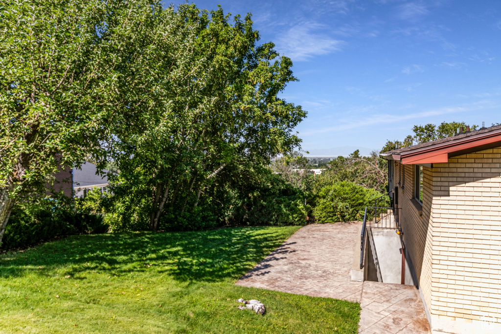 View of grassy yard featuring a patio
