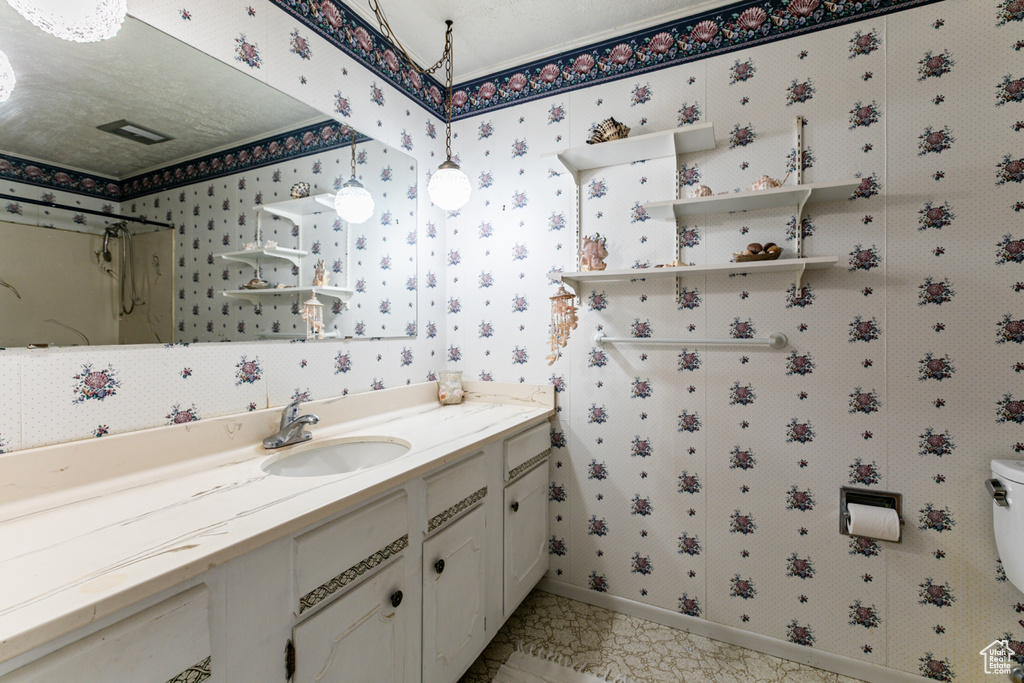 Full bathroom featuring vanity, a shower, and wallpapered walls