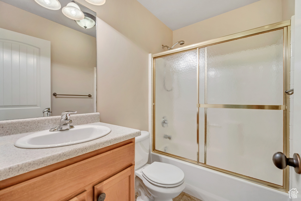 Bathroom with vanity and bath / shower combo with glass door
