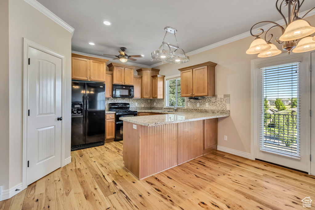 Kitchen featuring black appliances, a peninsula, ornamental molding, decorative backsplash, and light wood finished floors