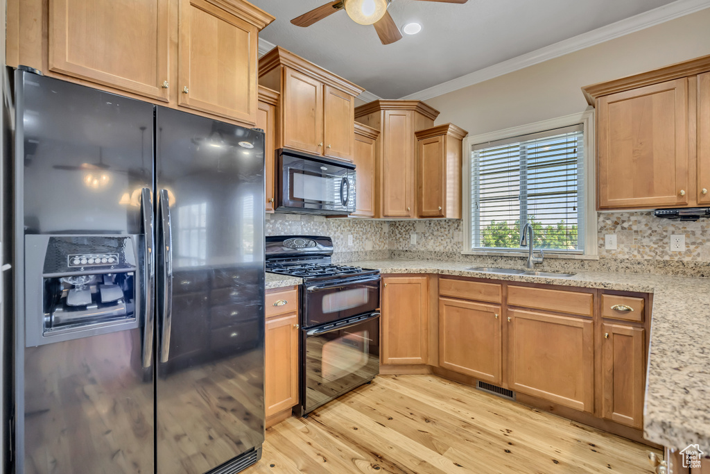 Kitchen featuring black appliances, ceiling fan, light wood-style floors, ornamental molding, and backsplash