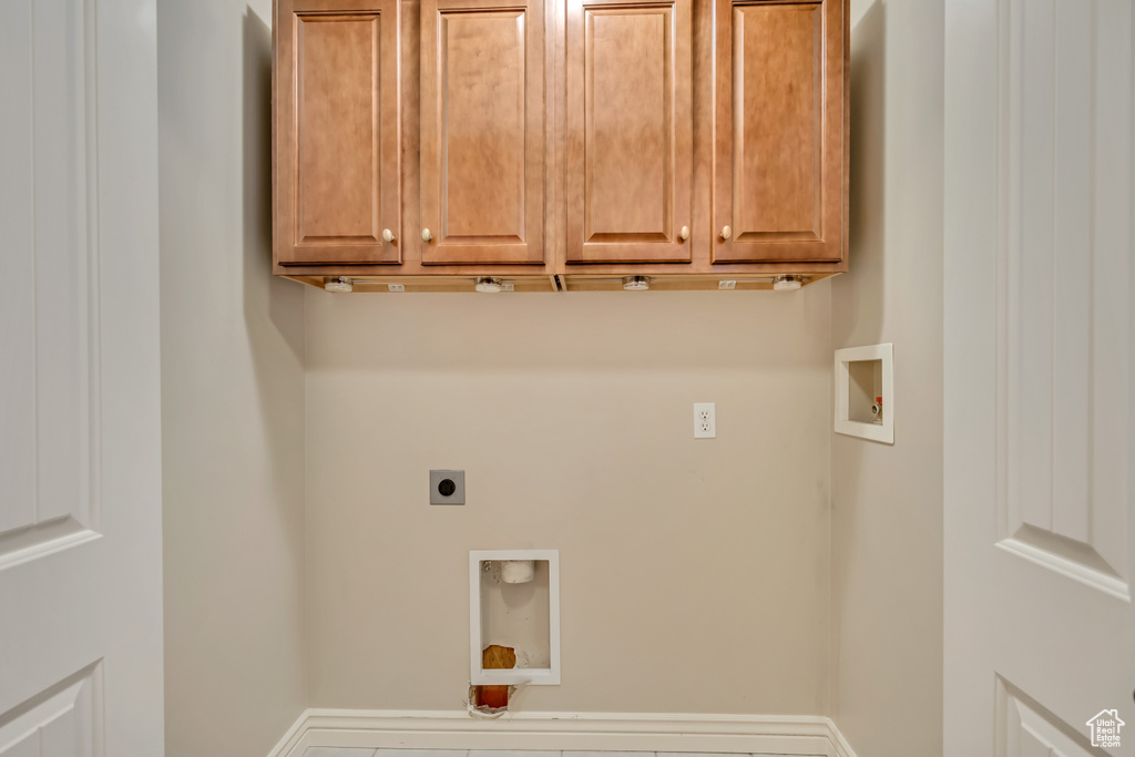 Washroom featuring electric dryer hookup, hookup for a washing machine, and cabinet space