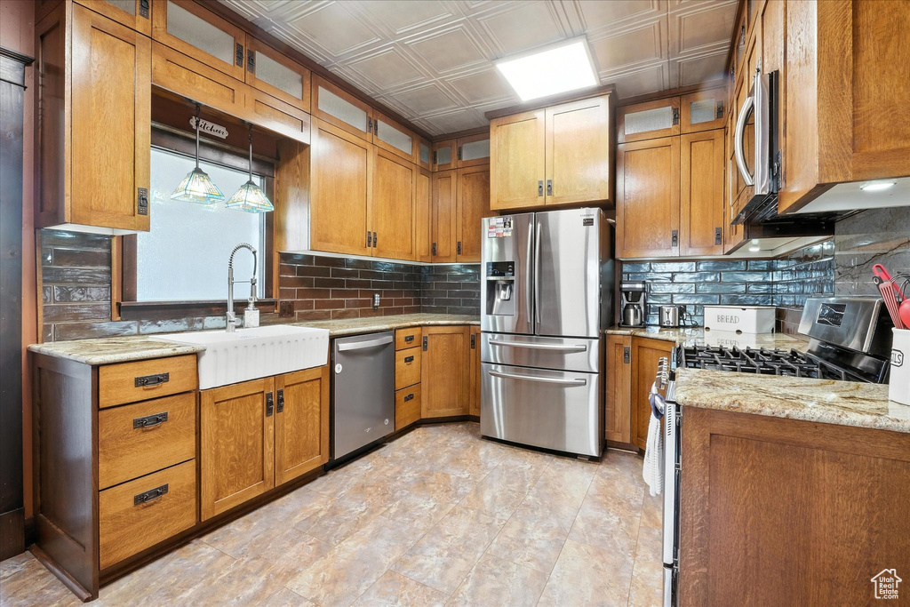 Kitchen featuring appliances with stainless steel finishes, brown cabinets, backsplash, and an ornate ceiling