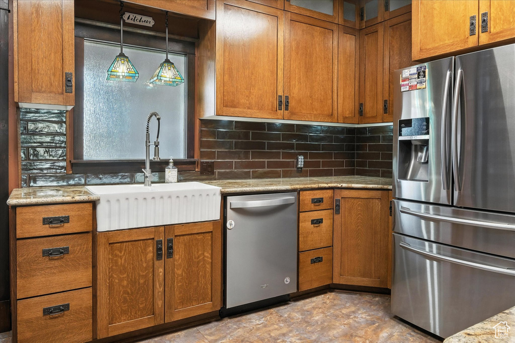 Kitchen with appliances with stainless steel finishes, brown cabinets, tasteful backsplash, and glass insert cabinets
