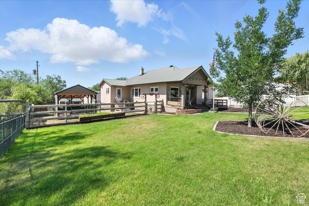 Rear view of house featuring a gazebo, a fenced backyard, a metal roof, and stucco siding