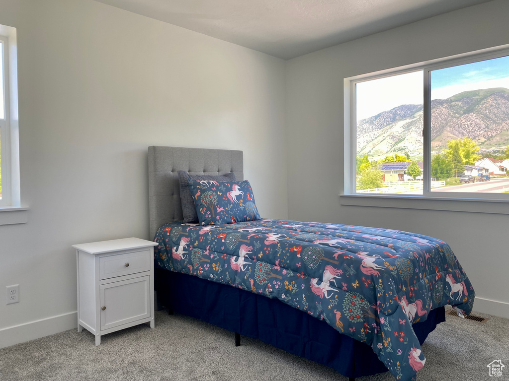 Bedroom with light colored carpet and a mountain view