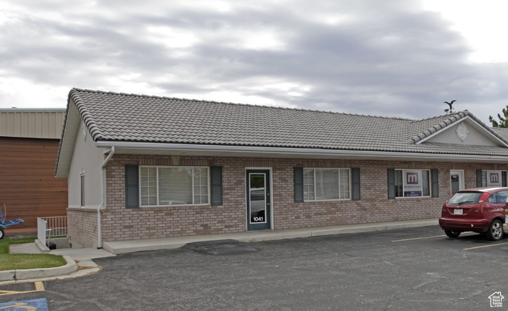 View of front of home with a tile roof, brick siding, and uncovered parking