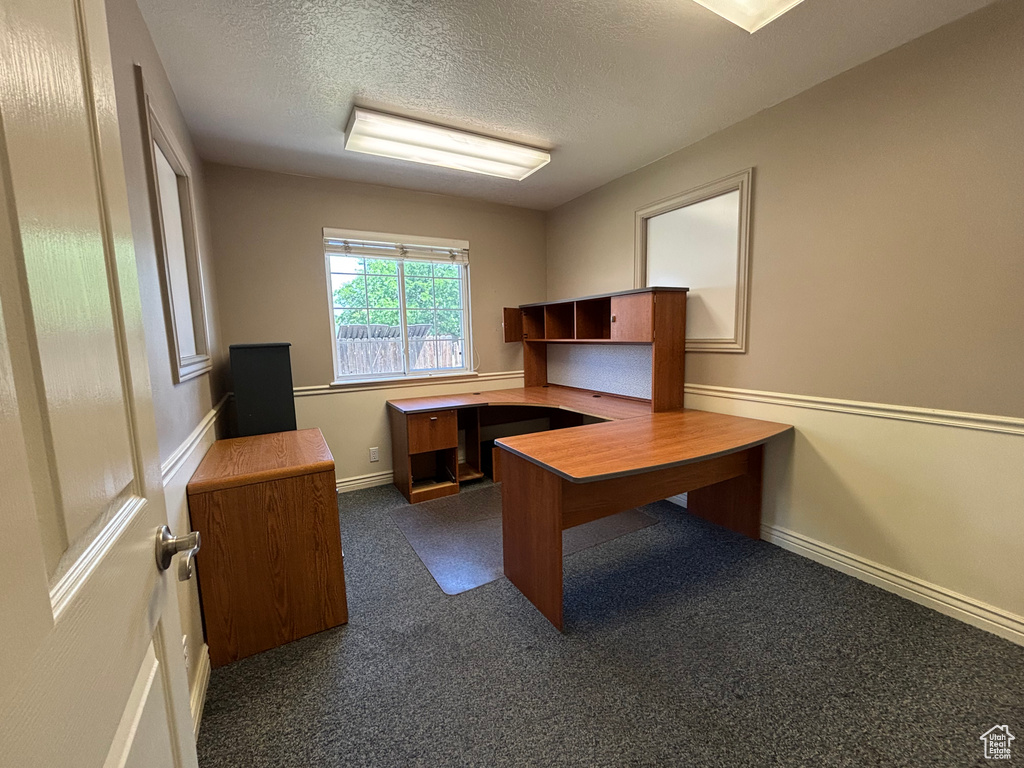Unfurnished office featuring a textured ceiling and dark carpet