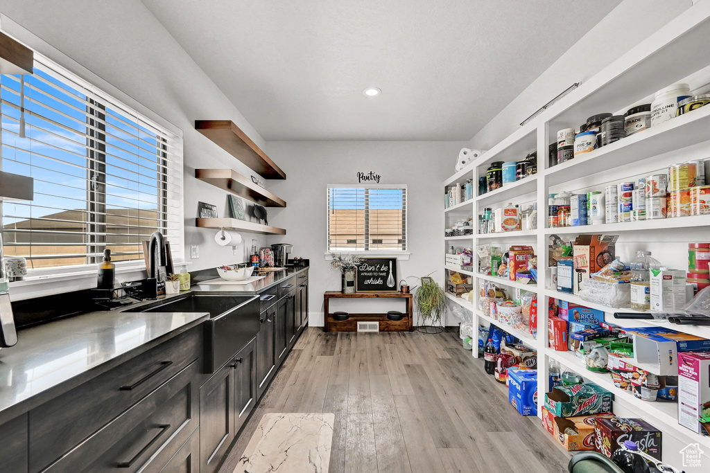 Kitchen with open shelves, light wood finished floors, dark cabinetry, and recessed lighting