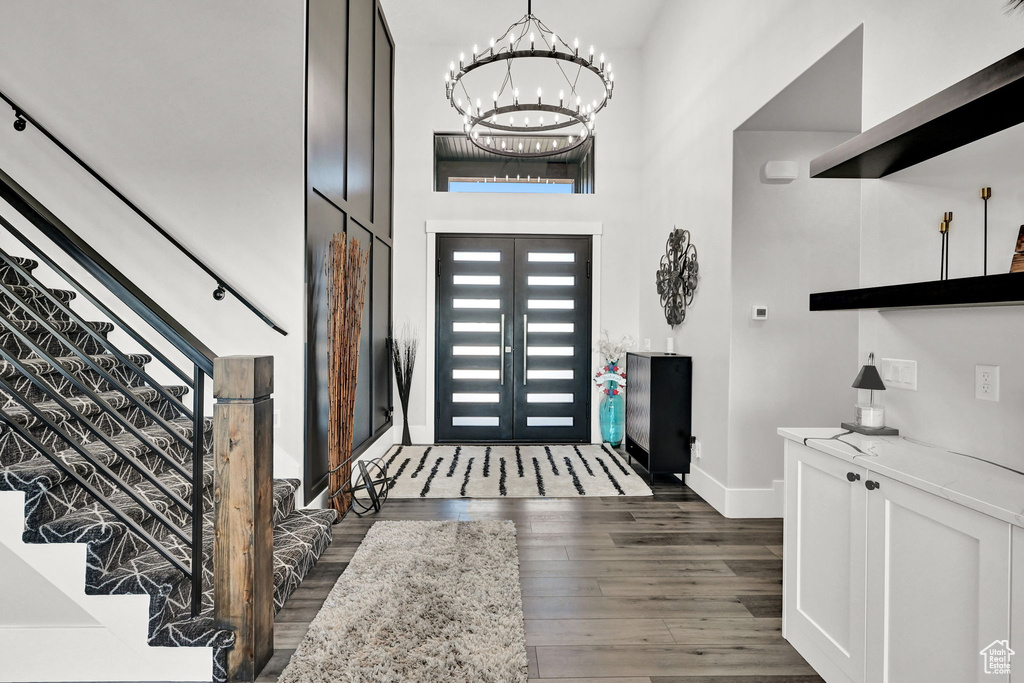 Foyer featuring a chandelier, wood finished floors, stairway, and a towering ceiling