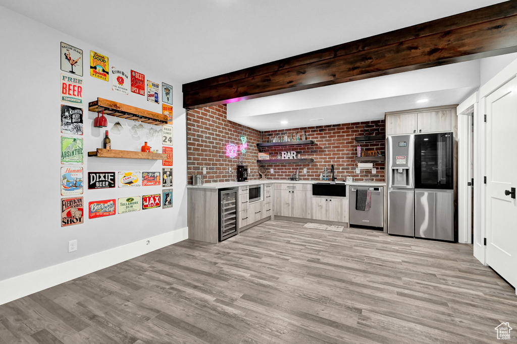 Kitchen featuring stainless steel appliances, beverage cooler, open shelves, light wood finished floors, and light countertops